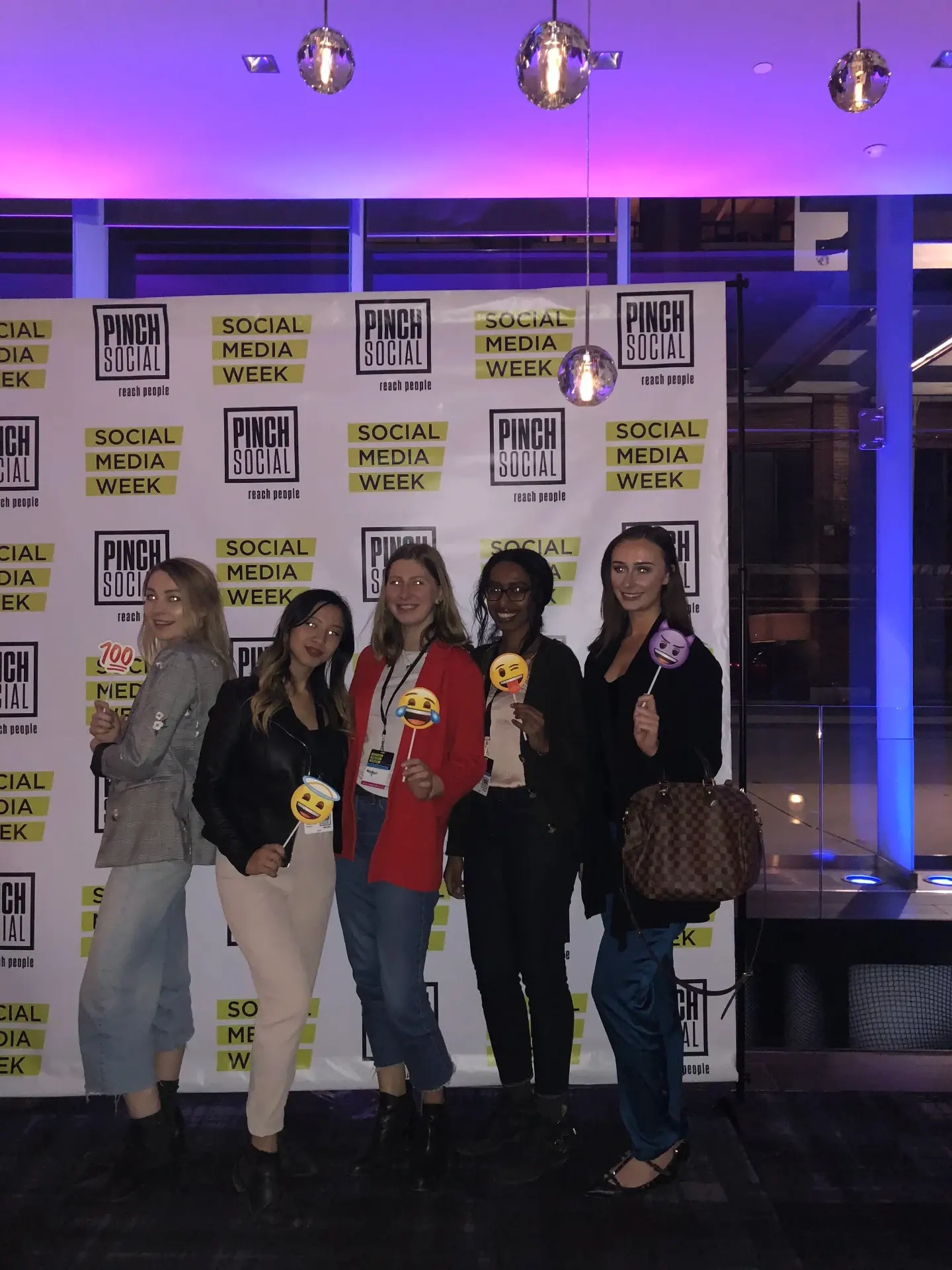 Brittany Garlin with colleagues holding emoji prop sticks at a Social Media Week step-and-repeat