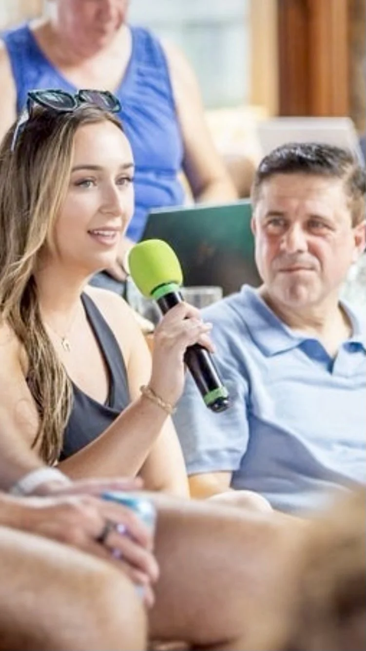 Brittany Garlin speaking with a lime-green microphone at a conference session
